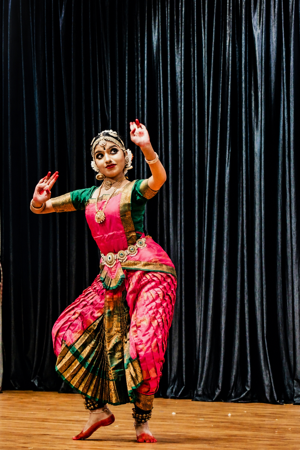 Bharatanatyam performer in red costume against a dark background